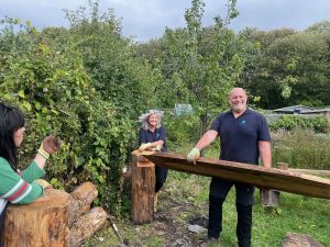 image of a man and woman from Aviva carrying a large length of wood ready to create a bench in an orchard